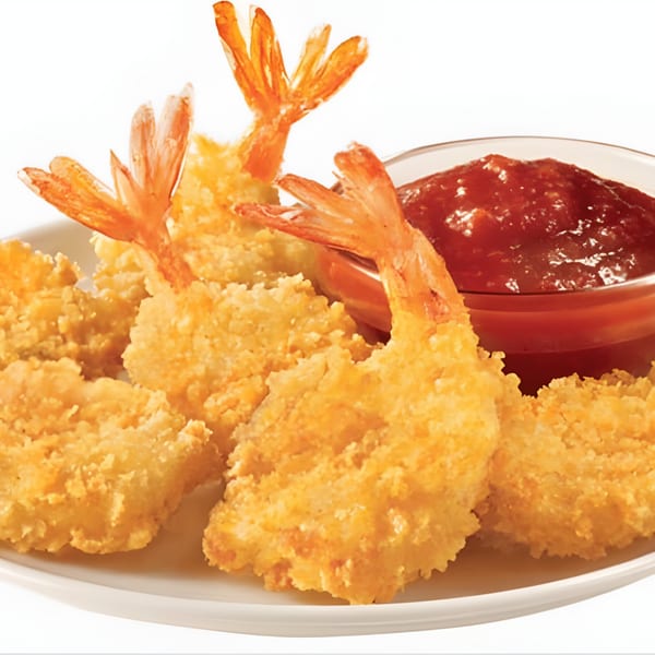 Crispy fried shrimp with tails on, served with a side of red dipping sauce.