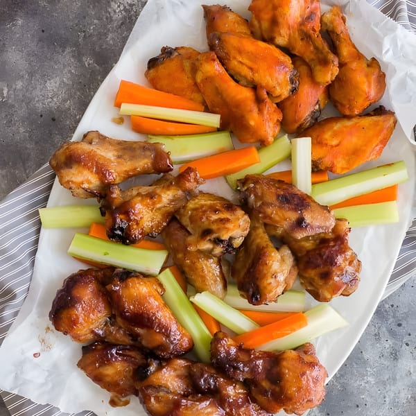 A platter of R Burger N Wings' glazed chicken wings with celery and carrot sticks.